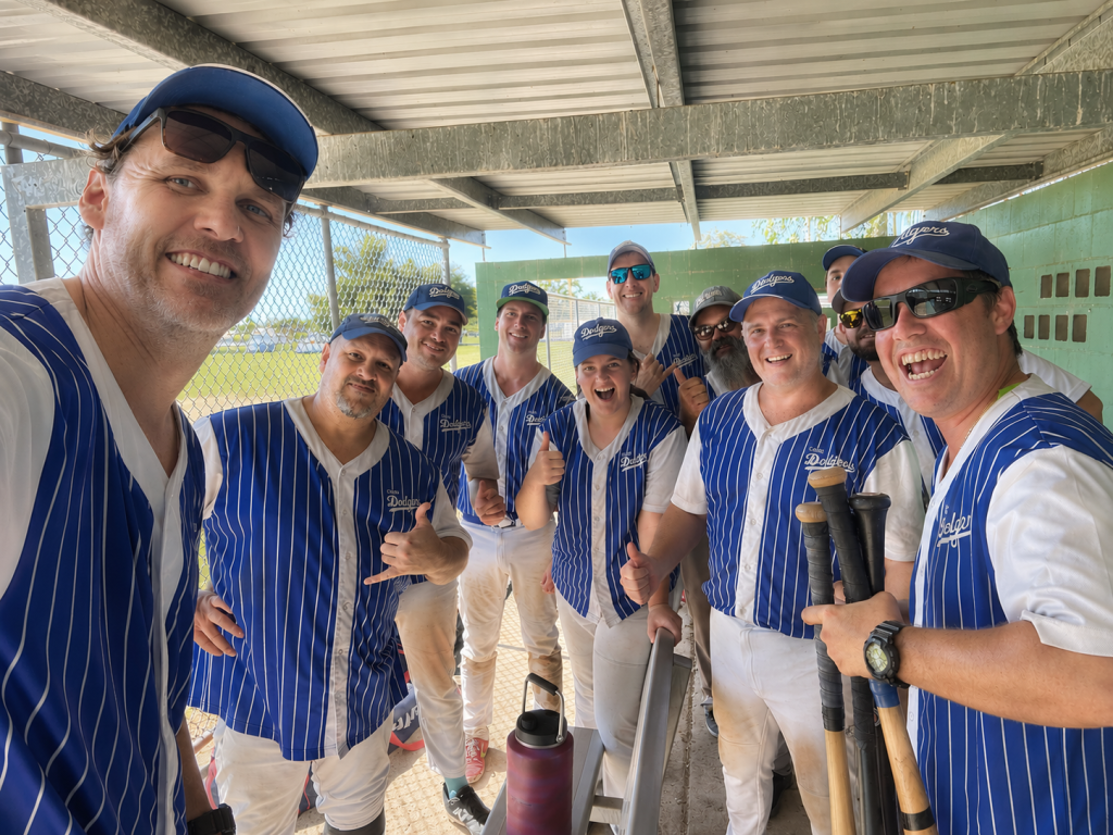 Group of baseball players in blue pinstriped uniforms posing for a selfie in the dugout.
