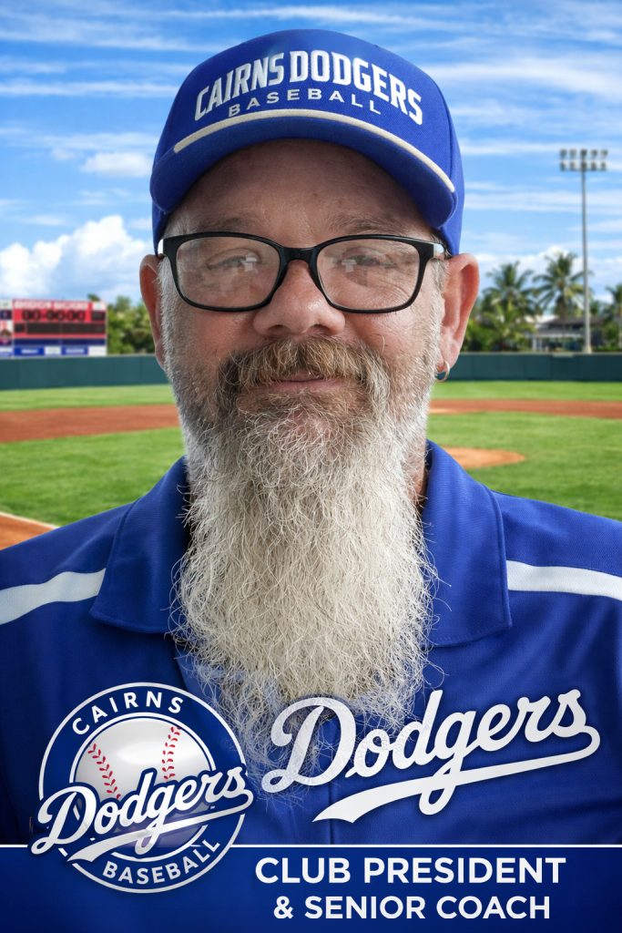 Portrait of a man with glasses and a long white beard wearing a blue Dodgers cap and polo, on a baseball field, with text on shirt reading 'Club President & Senior Coach'.